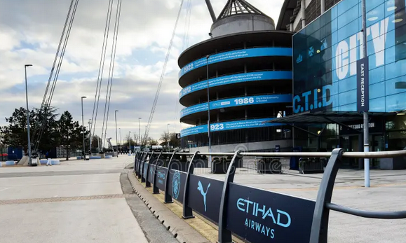 City Stadium Facade at Etihad Stadium in Manchester, UK, with Blue Banners and Large Screens Editorial Image
